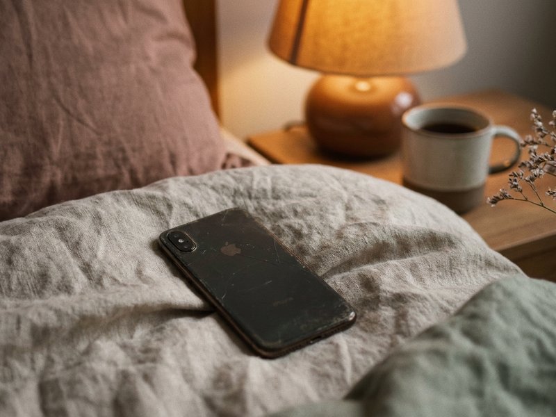 adhd friendship struggles — a phone face down on a linen blanket beside a warm lamp, lacedopamine.com