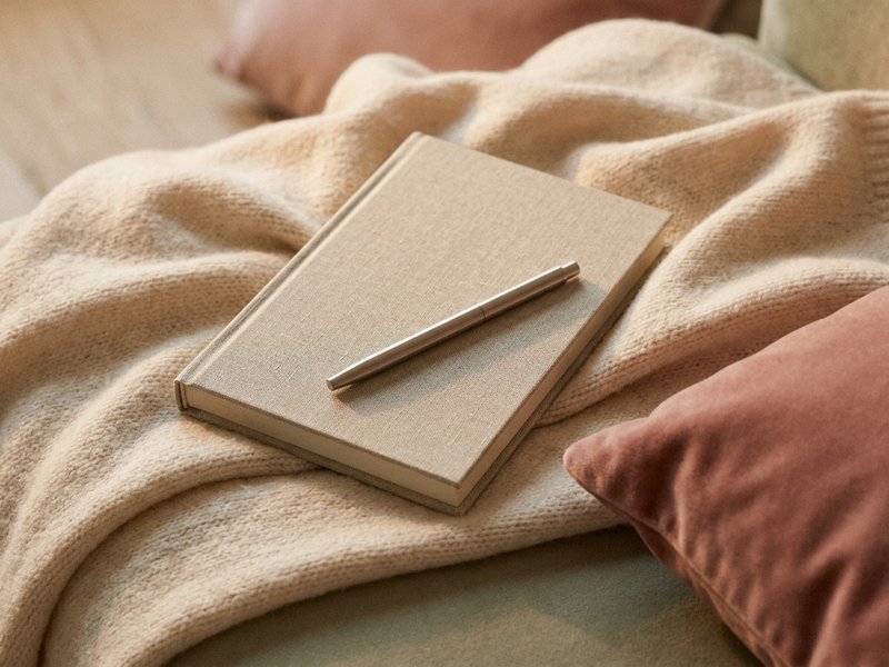 ADHD journal prompts — a notebook and pen resting on a soft blanket, lacedopamine.com