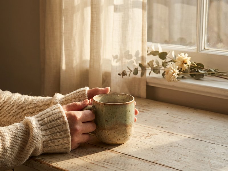 calming activities for adhd adults — hands wrapped around a warm mug beside a window, lacedopamine.com