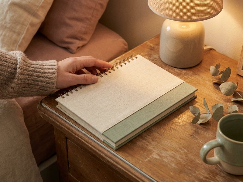 evening journal prompts ADHD — hands closing a notebook by lamp light, lacedopamine.com