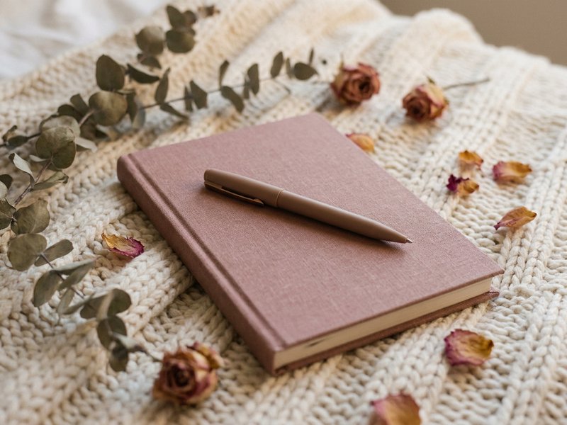 evening journal prompts ADHD — a journal and pen on a bed at dusk, lacedopamine.com
