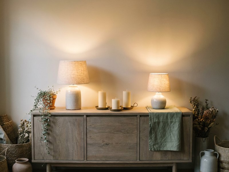 layered warm lighting for fall room refresh ADHD, small lamps and candles on a wooden sideboard, lacedopamine.com